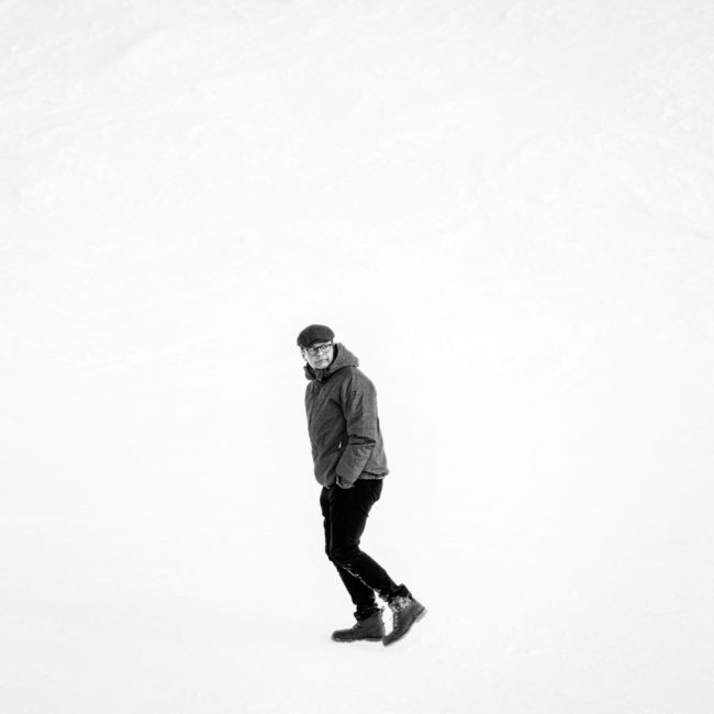Sort/hvid portræt af Anders Langblle, der går kun omgivet af sne.