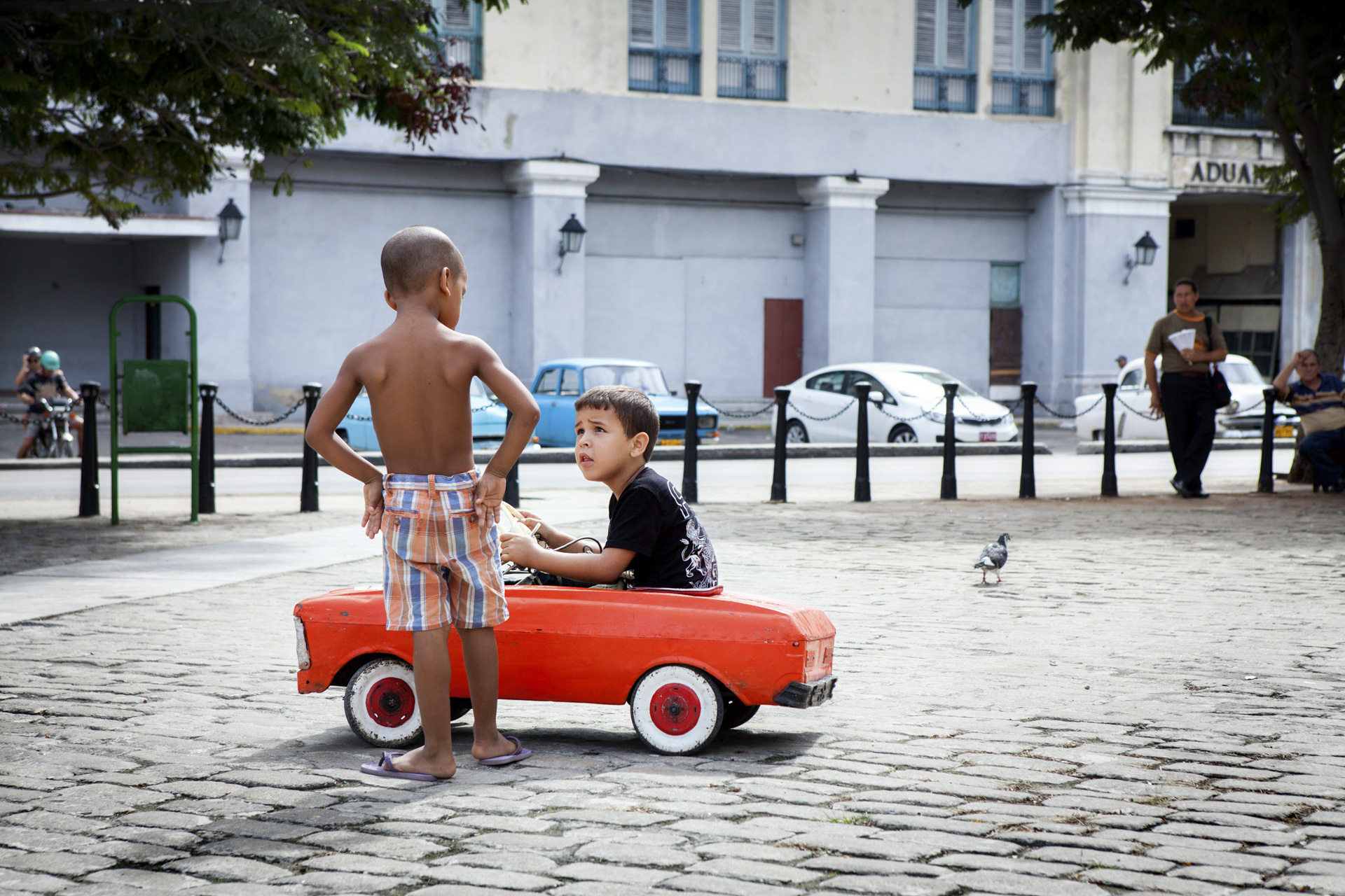 Small boys playing with a red car in a square in Havana, Cuba