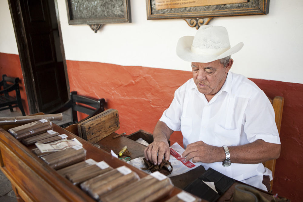 Older man wearing a white cowboy hat making cigars in Trinidad, Cuba