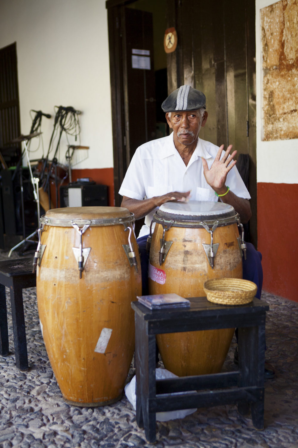 Older man wearing a six pence playing congas in Trinidad, Cuba